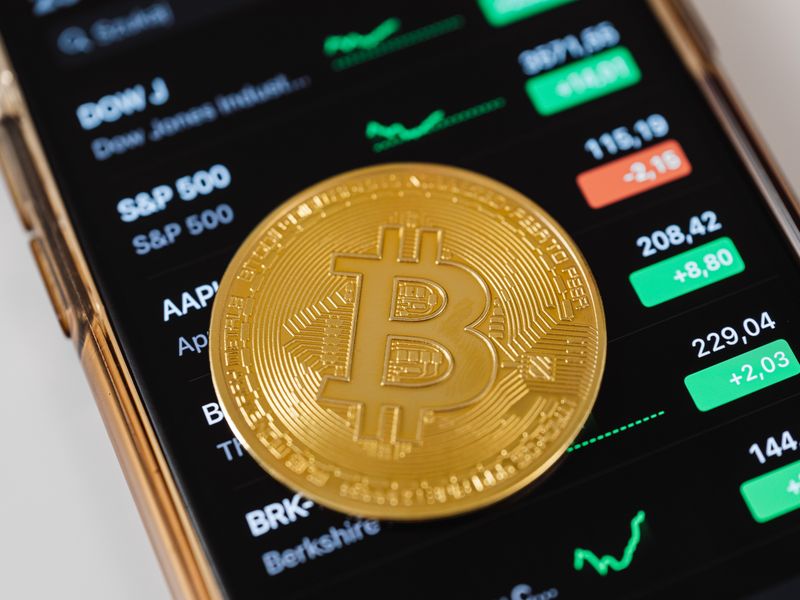 Schermata di app di investimento crypto mobile tenuta in mano, interfaccia scura